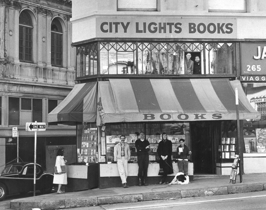 Four smiling patrons outside the original, smaller City Lights storefront, circa mid-1950s